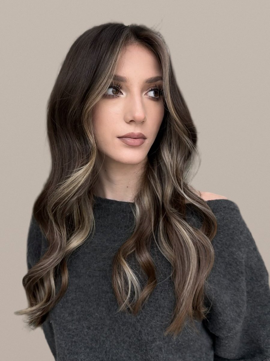 Șaten închis cu șuvițe blonde care încadrează fața și bucle lejere — lucrare realizată în salonul Inga Florea